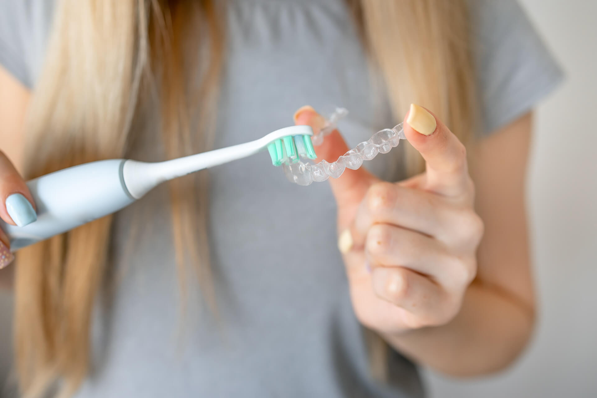 eine Nahaufnahme einer Person, die eine transparente Zahnschiene mit ihrer Zahnbürste putzt